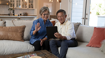 man and woman sitting on a couch looking at a tablet